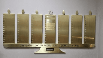 The Beth Joseph Yahrtzeit Memorial Board — brass plaques beneath a row of memorial candles